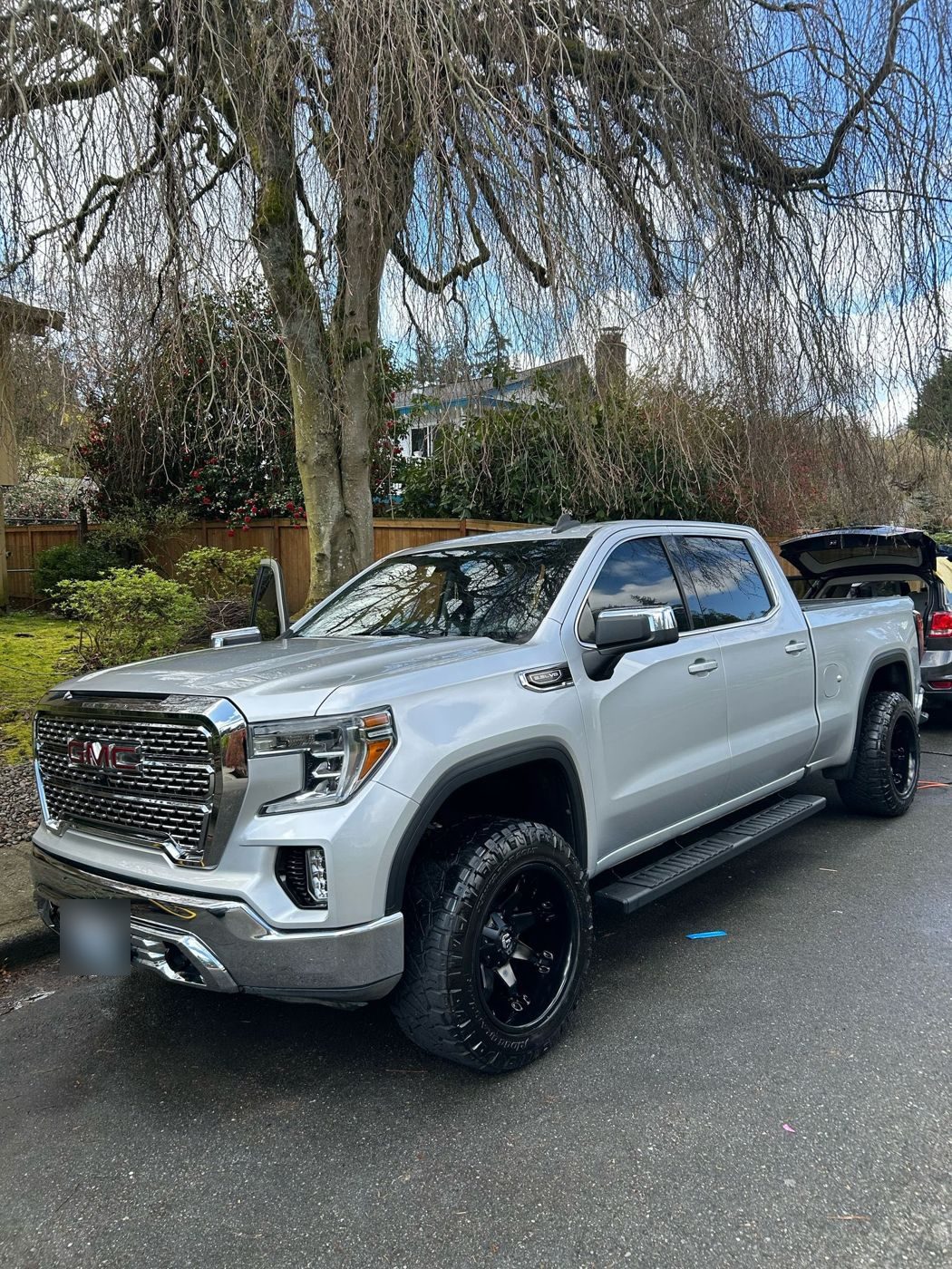 Silver GMC Sierra after a wash on a wet driveway