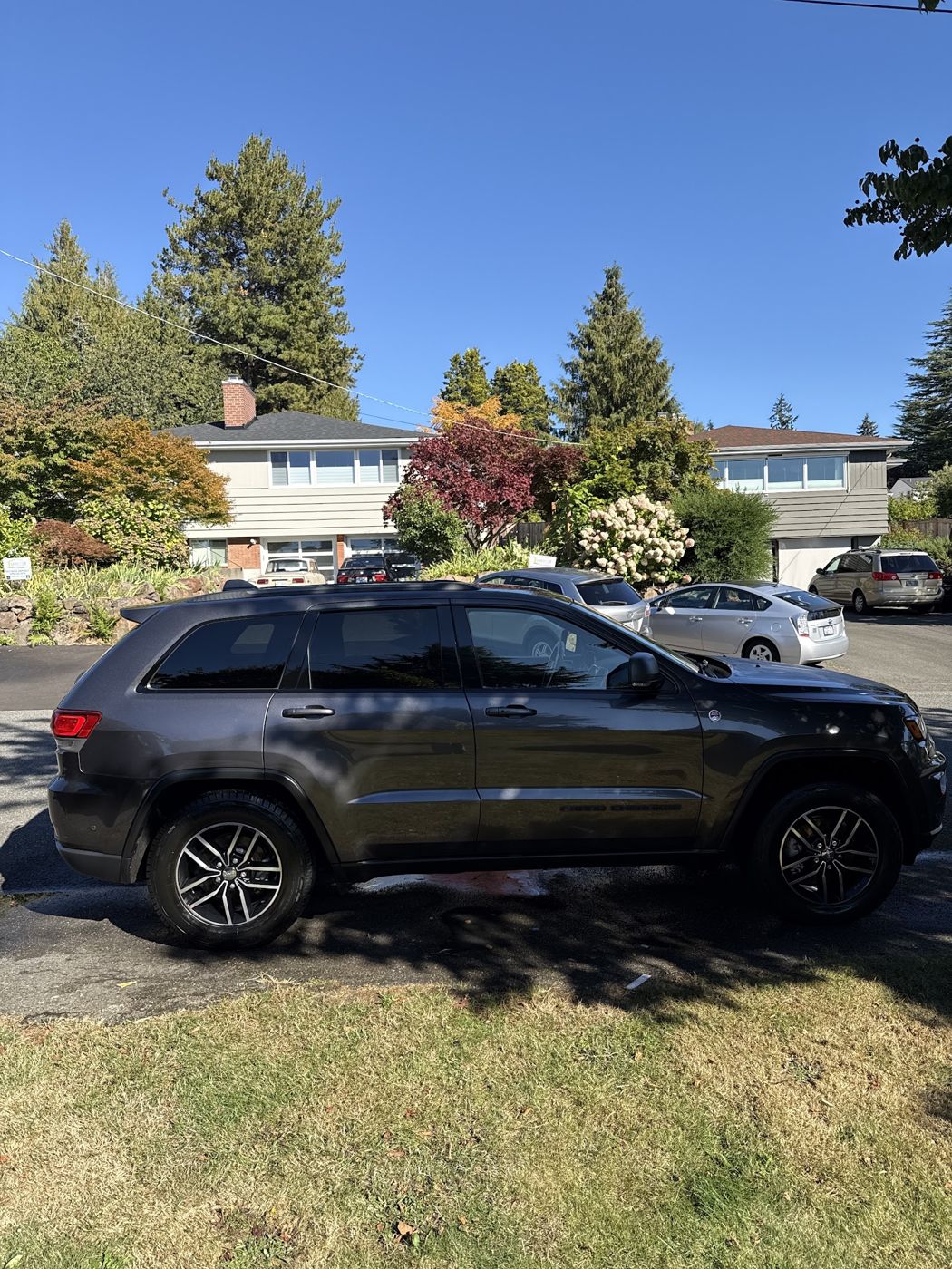 Dark Jeep Grand Cherokee gleaming on a sunny residential street